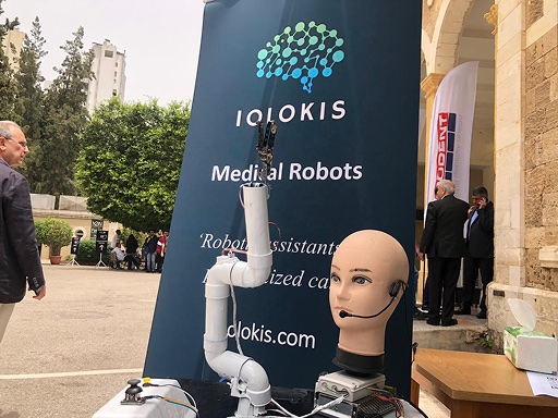 The io-arm prototype, a white robotic arm, on a table next to a mannequin head wearing a headset